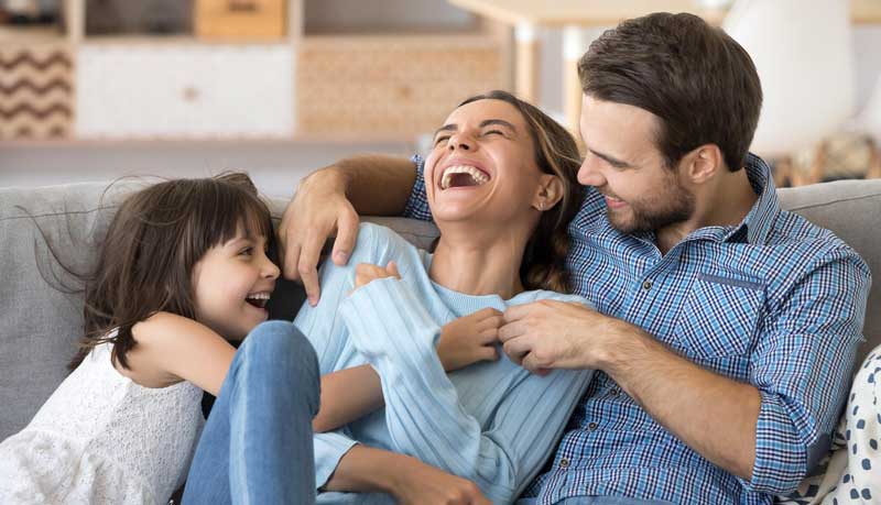 Woman laughing and joyful with husband and daughter, family mental health wellbeing