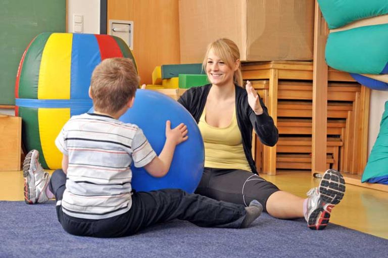 Pediatric occupational therapist with child in gym